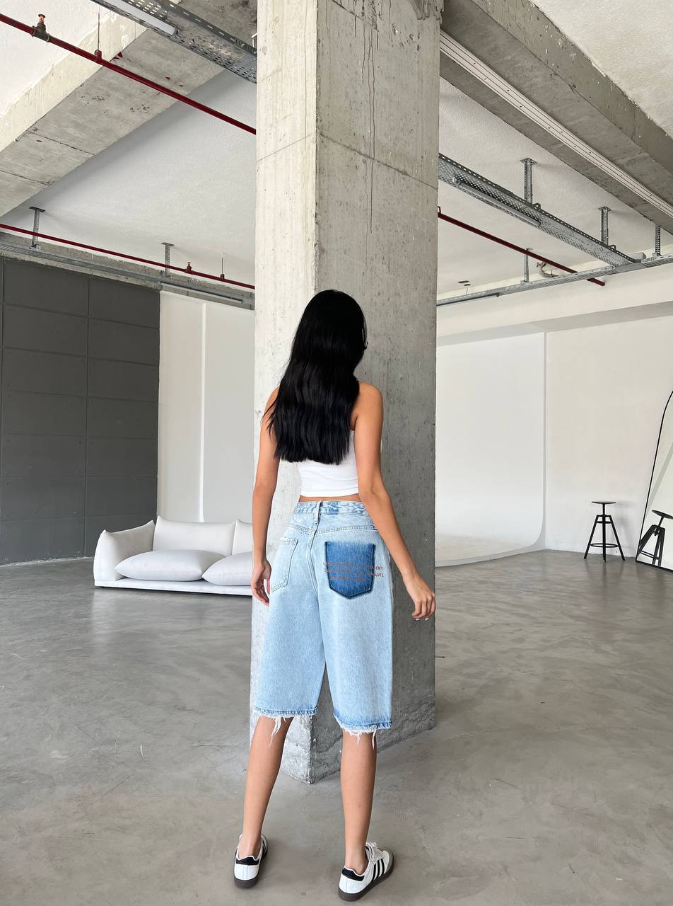 Bermuda shorts feature a relaxed, wide-leg silhouette that hits just above the knee, finished with a raw, frayed hem for a lived-in feel.