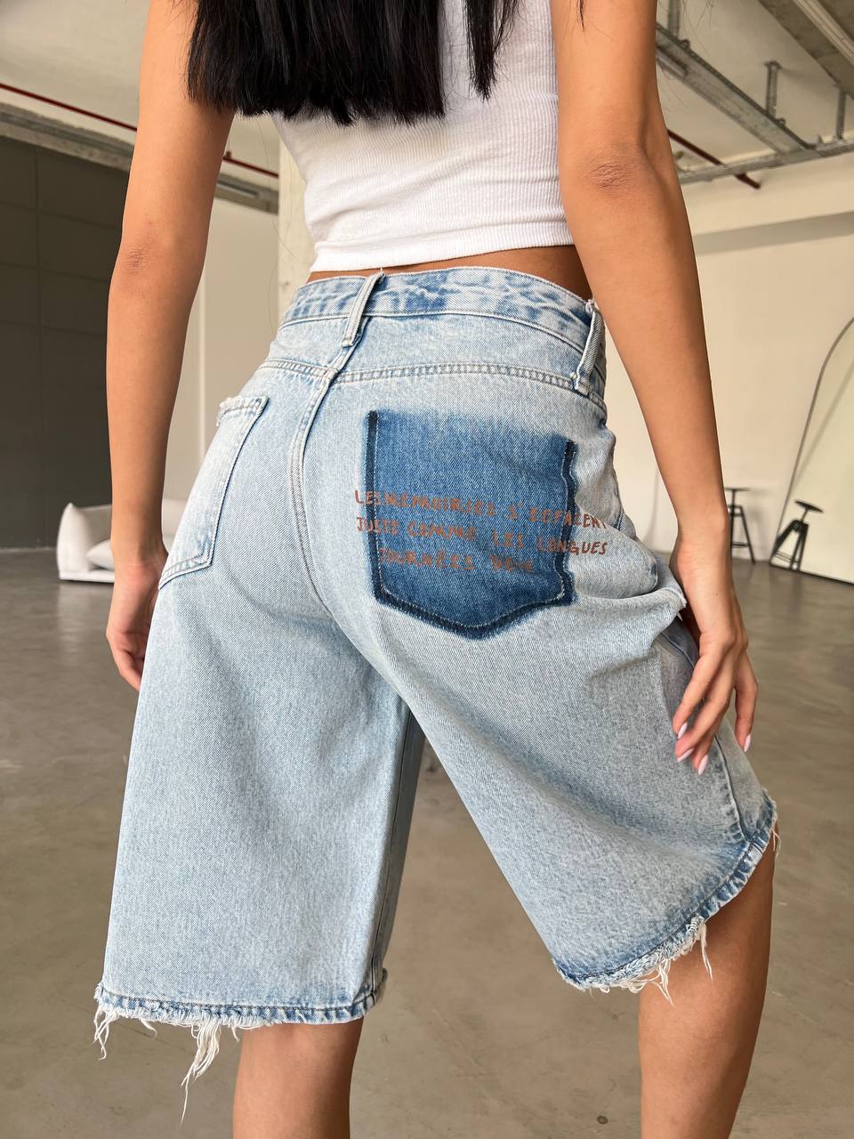 Bermuda shorts feature a relaxed, wide-leg silhouette that hits just above the knee, finished with a raw, frayed hem for a lived-in feel.