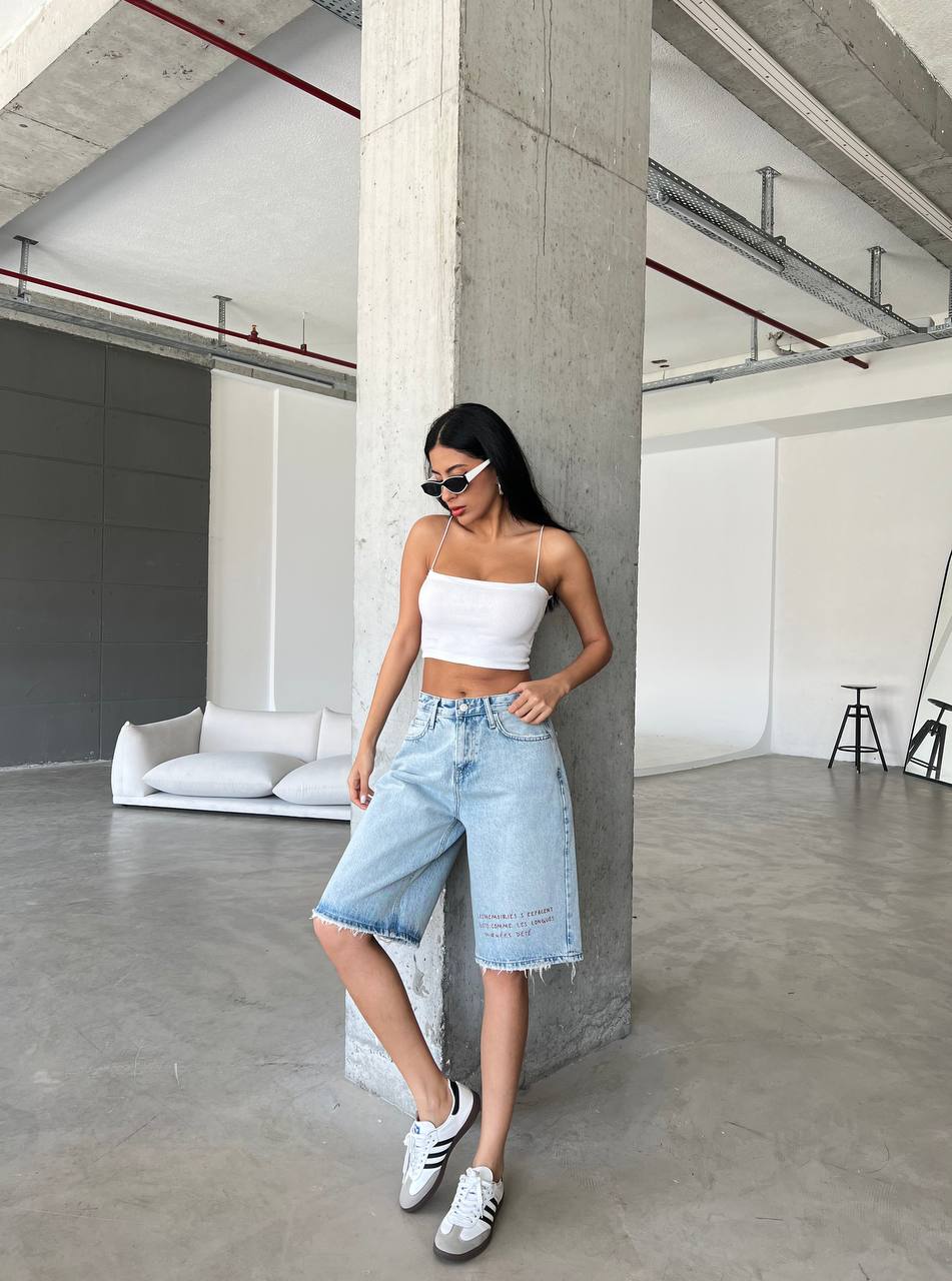 Bermuda shorts feature a relaxed, wide-leg silhouette that hits just above the knee, finished with a raw, frayed hem for a lived-in feel.